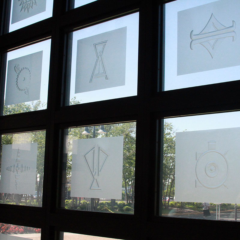 A group of glass etchings in a window grid.