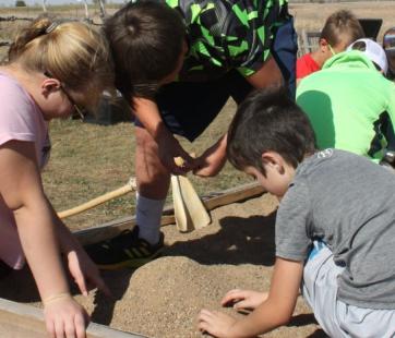 Children work in a garden setting with historic reproduction tools